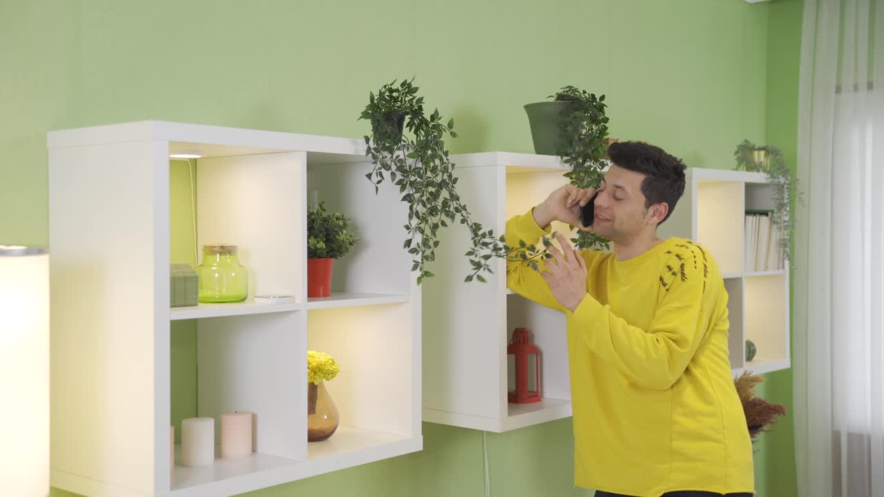 un joven divertido y juguetón hablando por teléfono en casa, sonriendo.