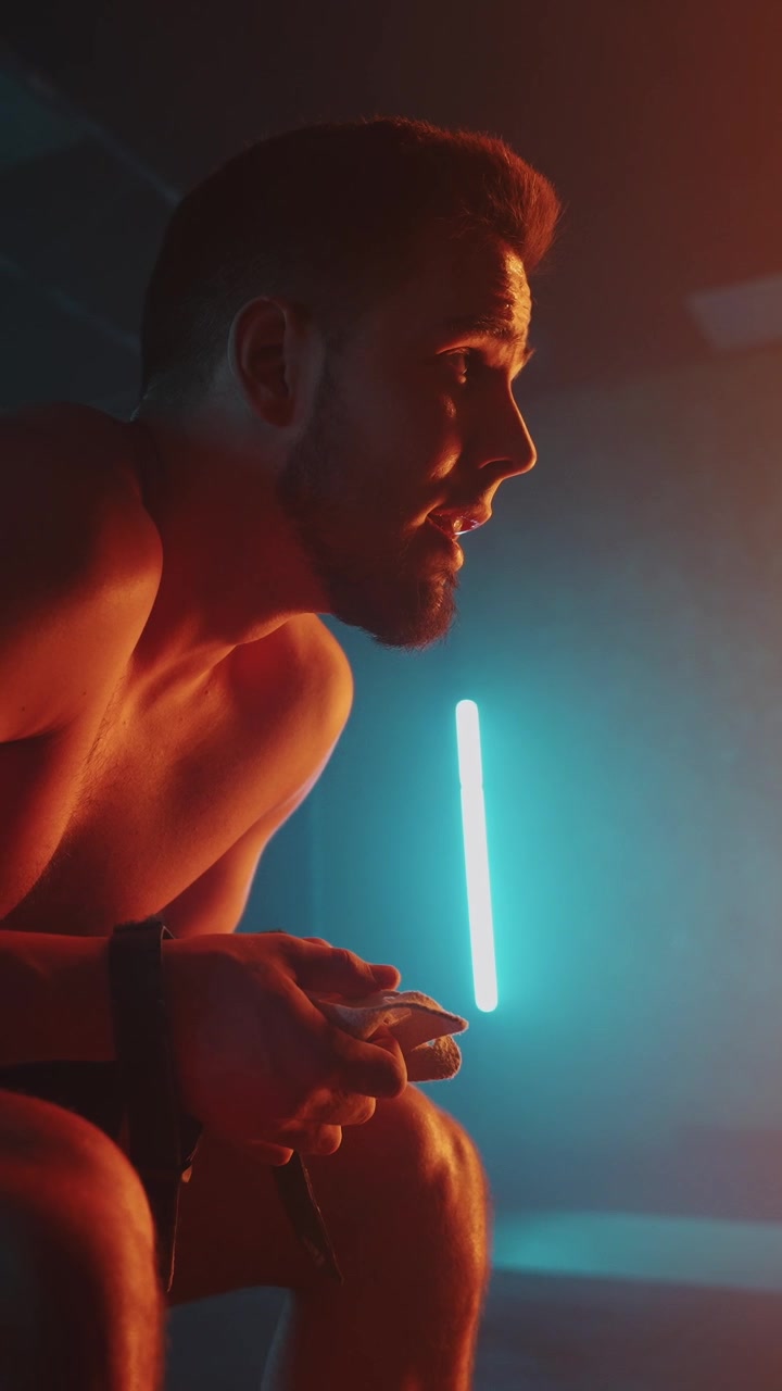 Atleta stanco che riposa in palestra con illuminazione al neon suggestiva