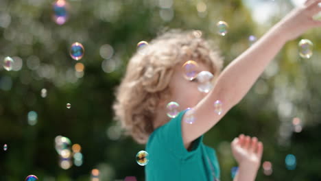 Süßer-Kleiner-Junge,-Der-Spielerisch-Seifenblasen-Fängt,-Die-Mit-Einem-Glücklichen-Kind-Schwimmen,-Das-Spaß-Daran-Hat,-Blasen-Im-Sonnigen-Park-Zu-Platzen,-Unbeschwertes-Kindheitsspiel-4k