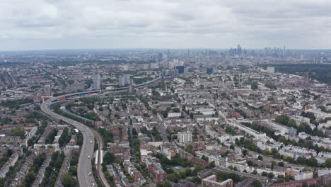 Aerial-panoramic-sliding-view-of-cityscape.-Transport-infrastructure-going-through-residential-district.-London,-UK