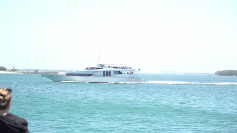 Woman-sitting-by-the-ocean-thinking-while-watching-a-yacht-drive-past