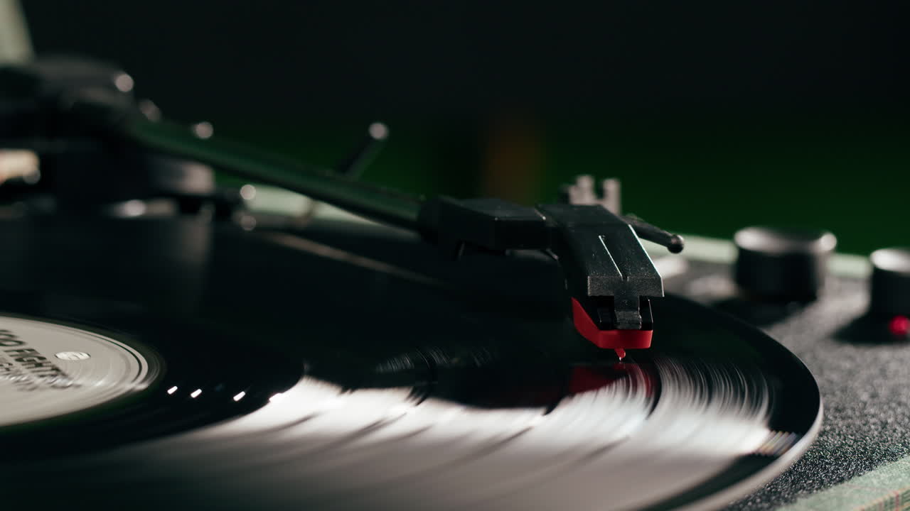 Primo piano di una mano che posiziona la puntina su un disco in vinile che gira