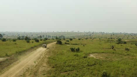 car speeds along dirt road to destination through african wilderness with green vegetation