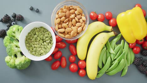 Video-of-fresh-fruit-and-vegetables-and-bowls-of-nuts-and-seeds-over-grey-background