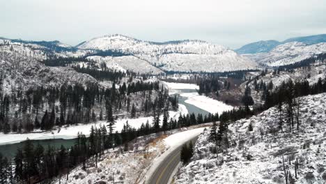 winter in british columbia: aerial shot follows yellowhead highway 5 through the frozen north thompson river valley near kamloops, snowy landscape panoramic view
