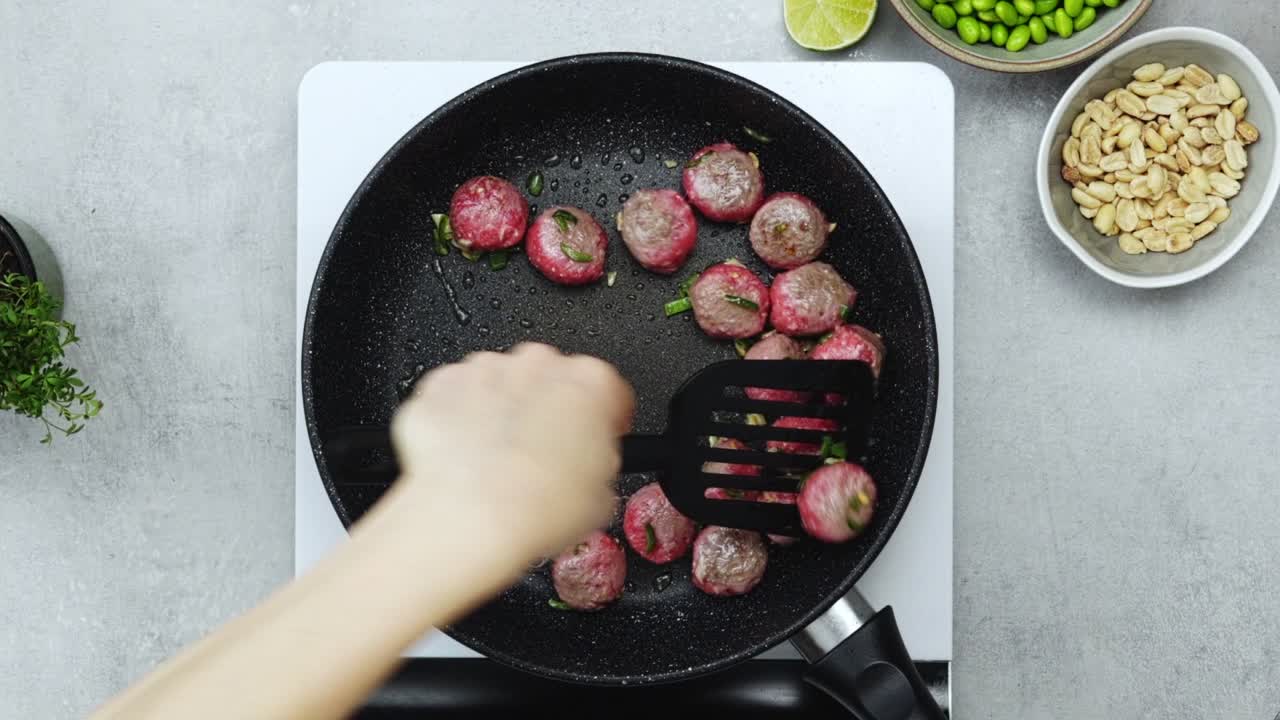 Woman cooking meatballs on frying pan with oil
