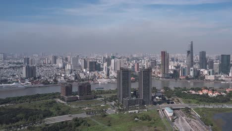 Aerial-hyperlapse-Vietnam,-Ho-Chi-Minh-City-Skyline-panorama-on-sunny-clear-day-featuring-architecture,-Saigon-River-and-Cruise-Ship