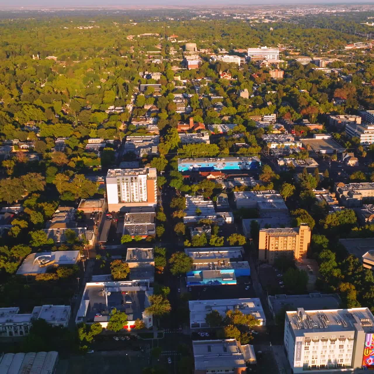 Vast urban panorama with lots of greenery on sunny daytime. Dense architecture of the city from aerial perspective