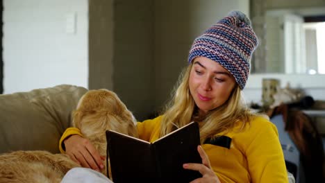 Woman-reading-book-with-her-dog-on-sofa-4k