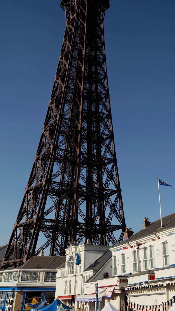Low-angle video shot of a tall iron tower against a clear blue sky, capturing the contrast between