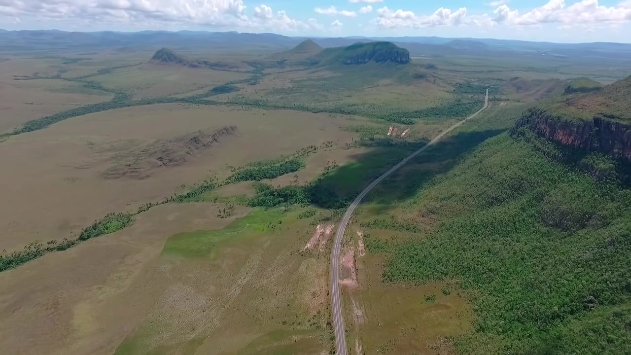 La GO-239 attraversa il Cerrado accanto al Morro da Baleia ad Alto Paraiso de Goias, Goias, Brasile, Sud America, rivelando l'altopiano della Chapada dos Veadeiros, ripresa aerea con drone ad alta quota, pullback con parallasse e inclinazione verso l'alto