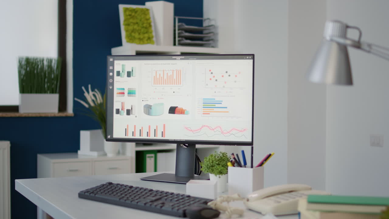 Empty desk with computer monitor showing financial statistics charts