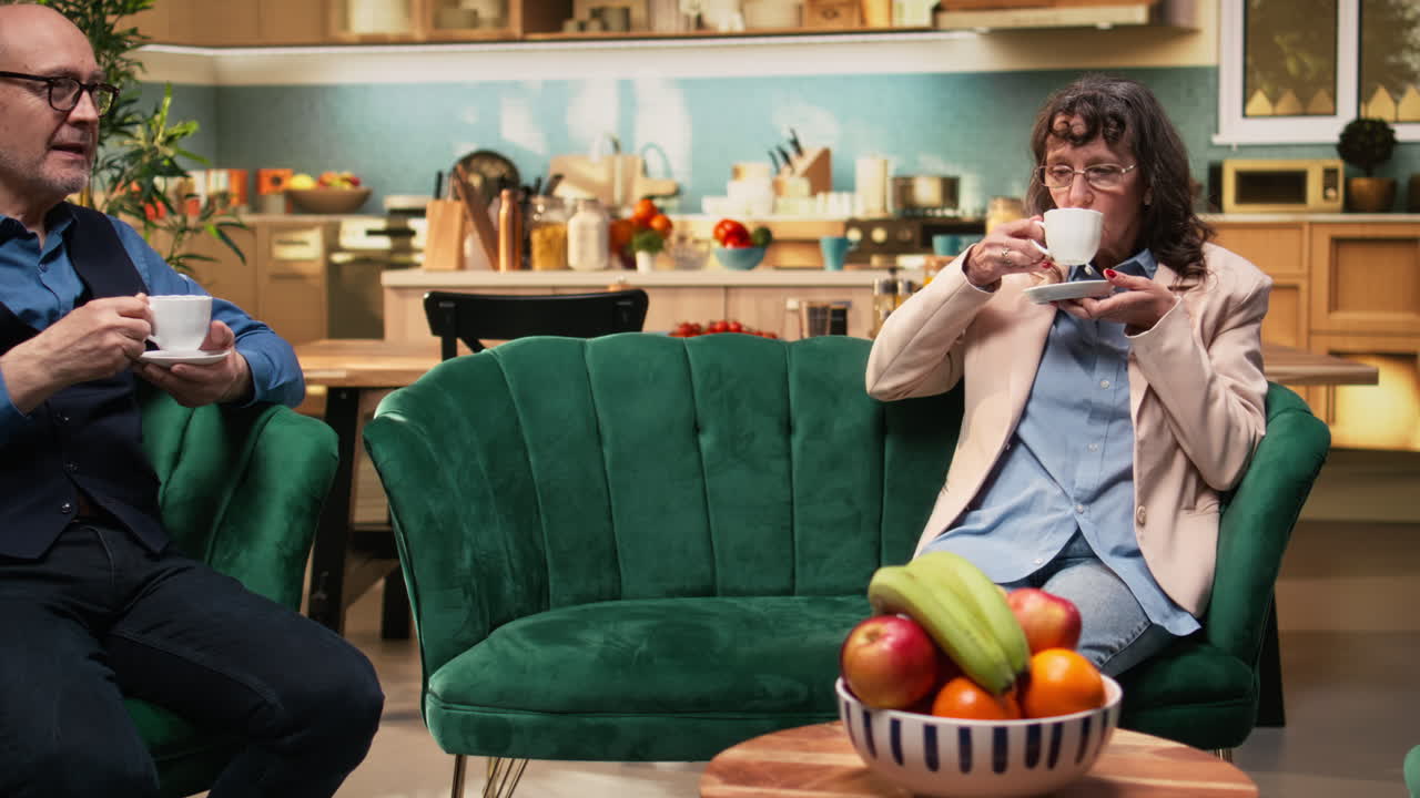 Senior man and woman daydreaming and relaxing with coffee cups on sofa