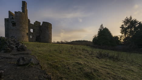 time lapse of a medieval castle ruin in rural countryside of ireland during sunset evening