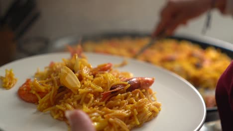 cook serving delicious plate of fideua with prawns for clients in valencian restaurant