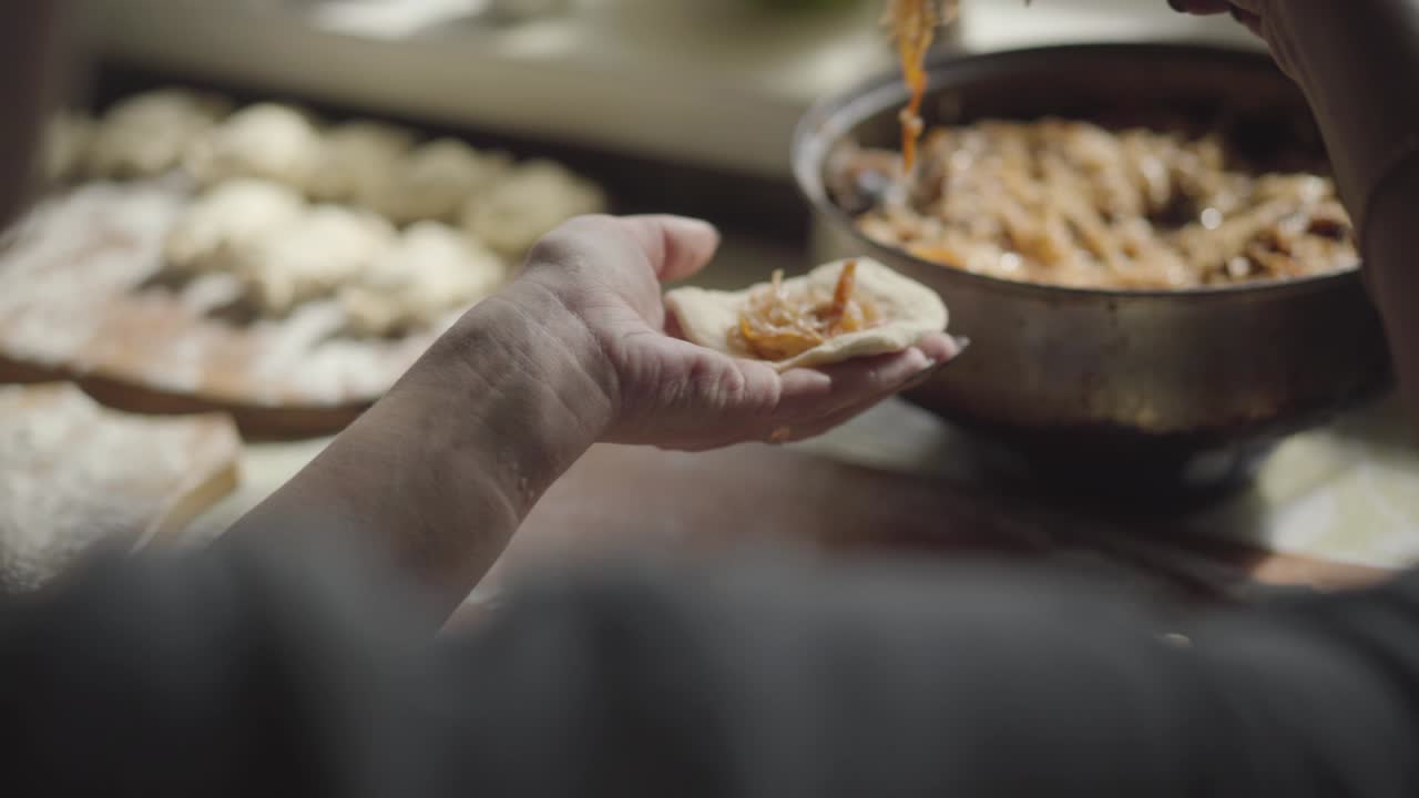 Unrecognizable Caucasian woman sculpting dumplings. Female hands putting cabbage into dough circle. Cooking, cuisine, culinary, traditional Ukrainian food.