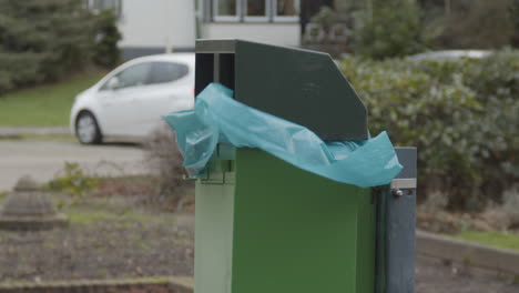 plastic garbage bag in green trashcan flapping in the wind - close up