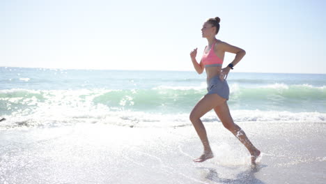 joven mujer caucásica corre a lo largo de la costa con espacio de copia