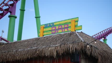 a beach bar sign under a rollercoaster at a holiday vacation resort