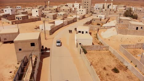 aerial-fast-moving-shot-of-empty-road-with-car-driving-in-at-next-to-some-soldiers-in-palestine-arabic-empty-city-near-gaza