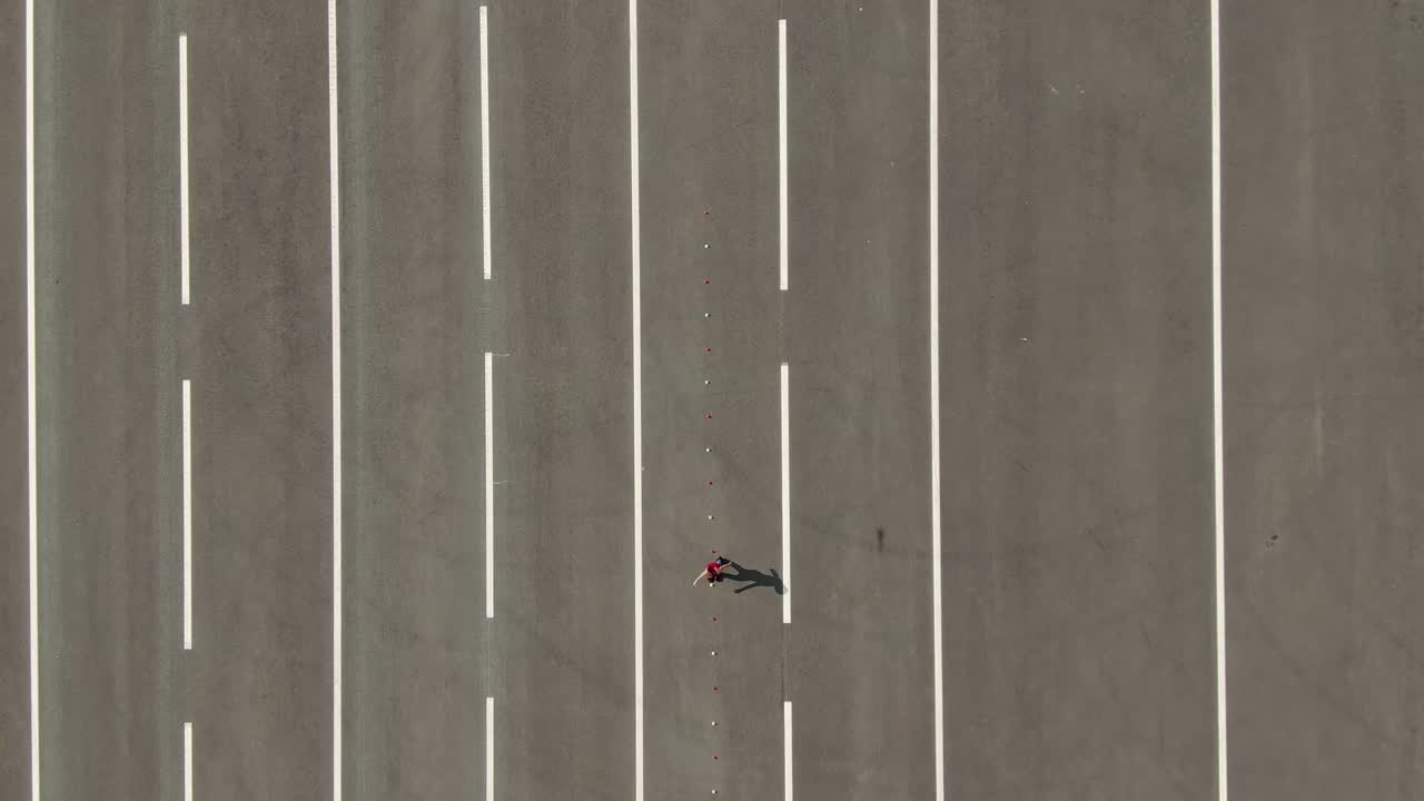 공중에서 볼 때, 여자 운동 선수가 광장에서 훈련합니다. 롤러 스케이트를 타고 있는 소녀가 코너를 돌아다닙니다. 헬기에서 볼 때. 4k, 10bit, prores