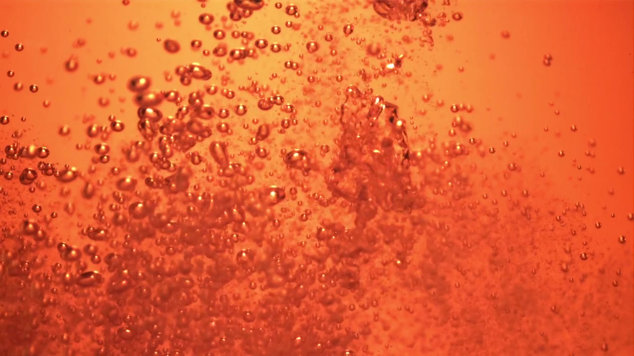 Close-up of Golden Bubbles Rising in Orange Liquid