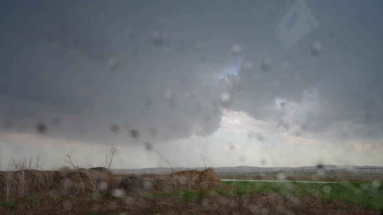 Regn falder ned ad en bilrude, mens mørke stormskyer truer ovenover