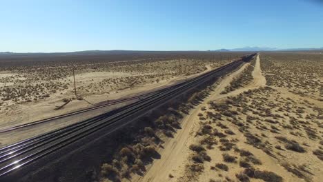 a dramatic aerial over a freight train as it travels at a high speed across a desert landscape