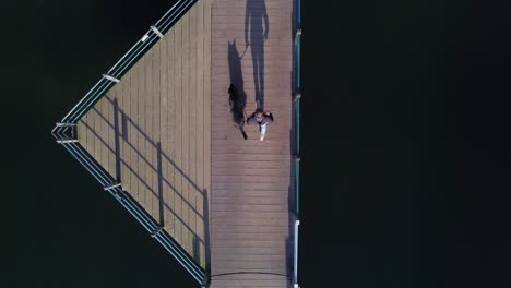 a guy walking his pet dog outside on a dock