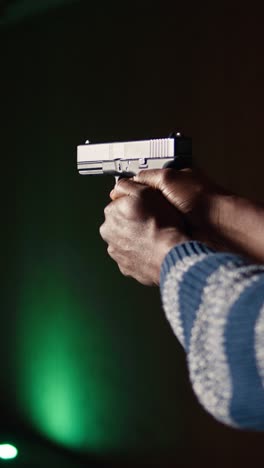 Vertical video Shooting range client shoots with pistol, engaging targets, close up