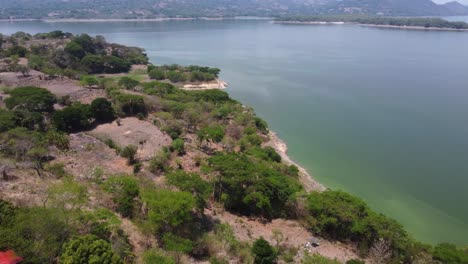 aerial flyover: rugged hilly lake shore in tropical el salvador mtns