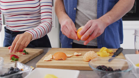 video of midsection of diverse couple preparing fruits for juice