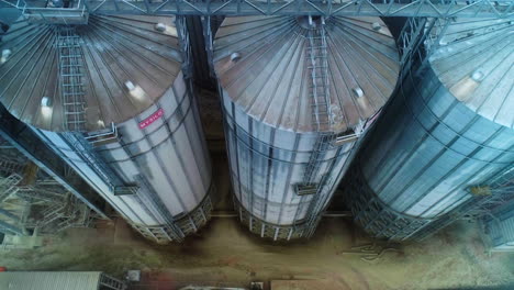huge mighty cisterns for grain storage at elevator plant. view on the metal tanks connected with each other by a support. aerial perspective.
