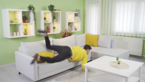 Funny-clumsy-young-man-trying-to-jump-on-the-sofa-at-home-but-fails.