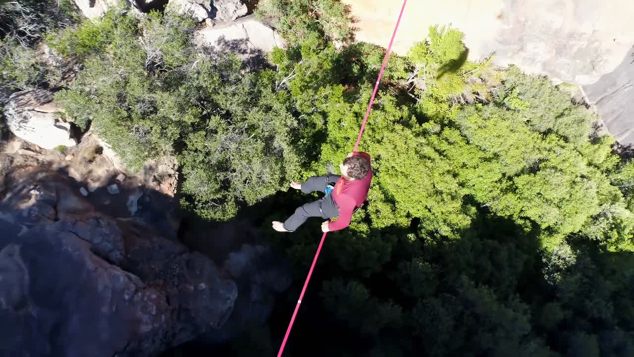 hombre highliner sentado en una cuerda sobre montañas rocosas 4k