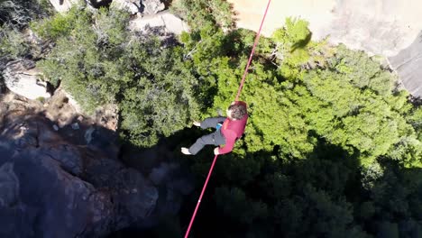 Male-highliner-sitting-on-a-rope-over-rocky-mountains-4k