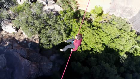 Male highliner sitting on a rope over rocky mountains 4k