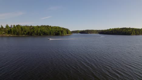 Aerial-view-following-a-boat,-driving-on-the-Baltic-sea,-archipelago-of-Sweden---pan,-drone-shot