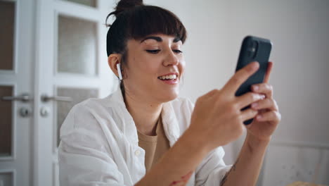 Artista-Sonriente-Sosteniendo-Un-Teléfono-Inteligente-En-Casa-De-Cerca.-Auriculares-Mujer-Escuchando-Música