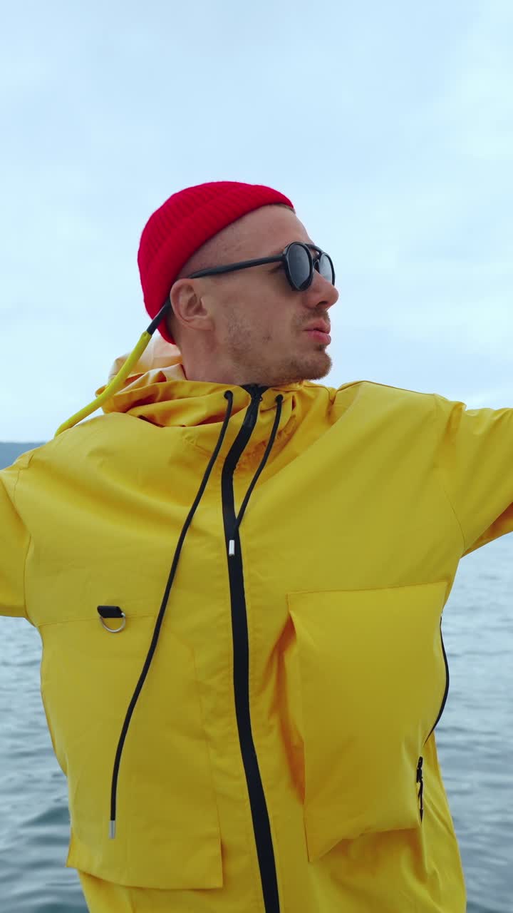 Mann in gelbem Regenmantel und roter Mütze auf dem Wasser