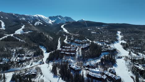 Aerial-view-of-ski-lodges-nestled-in-the-side-of-the-Telluride-mountains-on-a-sunny-winter-day