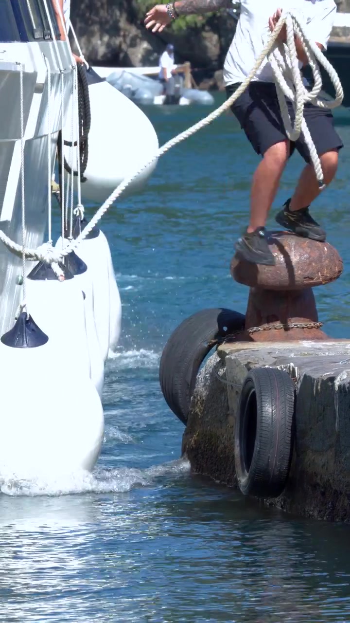 Un grande yacht bianco si avvicina lentamente a un molo di cemento per l'ormeggio in pieno giorno.