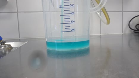 se vierten 360 ml de un limpiador químico azul en una taza medidora