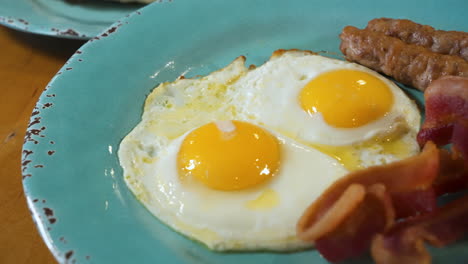 desayuno rico en proteínas de dos huevos soleados, tocino crujiente, salchichas, control deslizante de cerca 4k