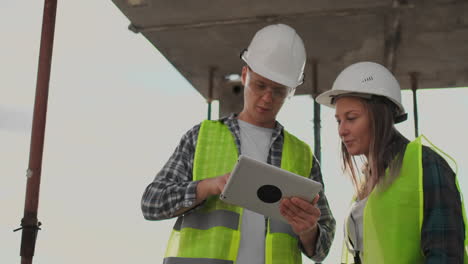 equipo de construcción o arquitecto y constructor o trabajador con cascos discuten un plan de construcción de andamios o un plan o una lista de comprobación