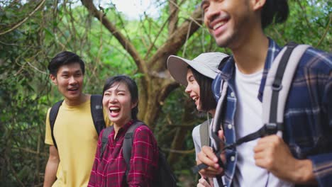 group of young asian man and woman friend traveling in the forest together. they are feeling fresh and relax in nature wild, looking and pointing the view then continue walking with happiness and fun.