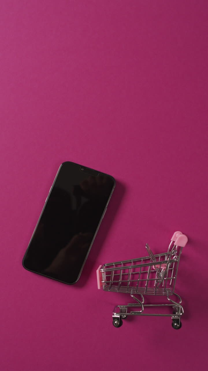 Video verticale di carrello della spesa con smartphone su sfondo rosa.