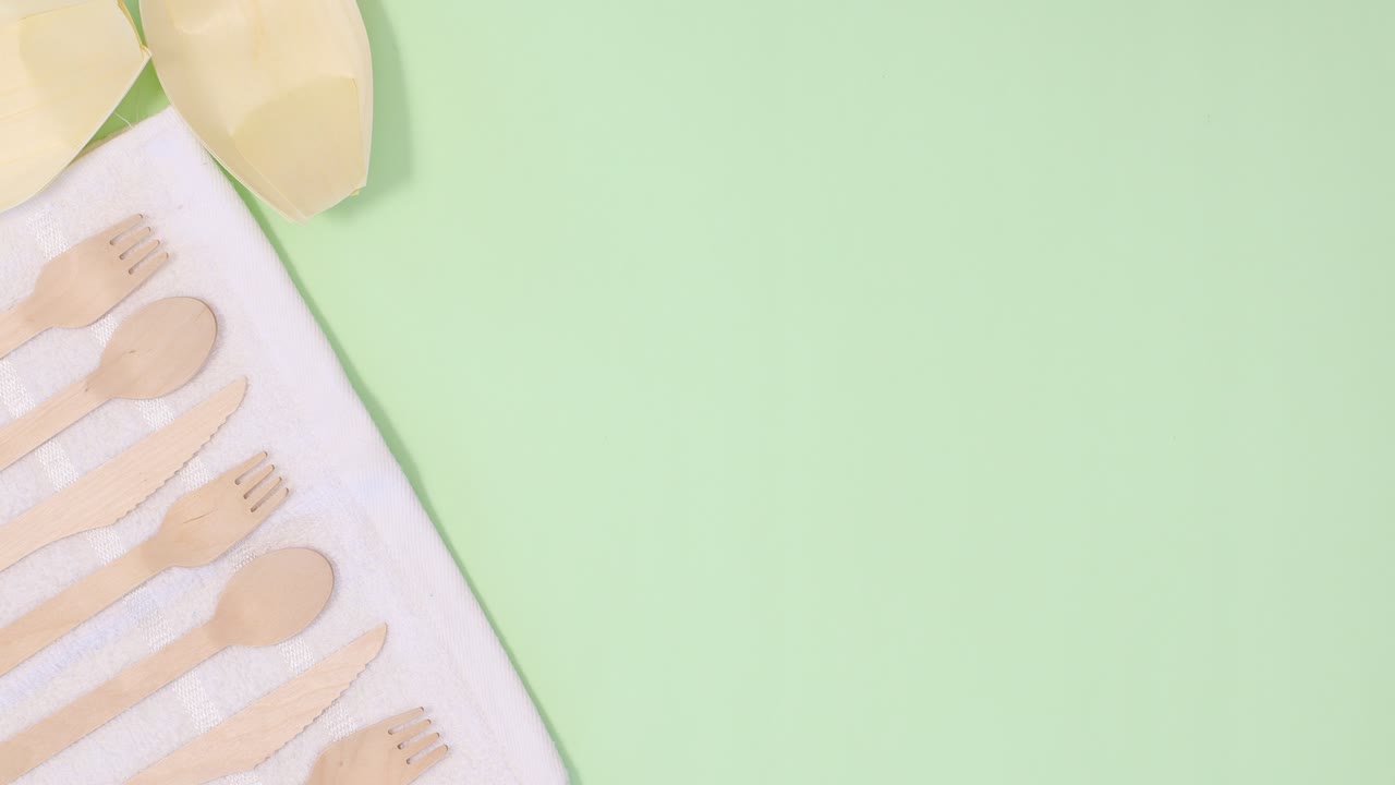 los utensilios ecológicos de cero residuos aparecen en tela blanca en el lado izquierdo del fondo verde claro.