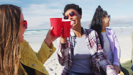 un grupo feliz de amigas diversas divirtiéndose, haciendo picnic en la playa
