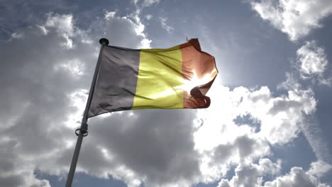 flag of belgium flapping in slow motion against a blue and sunny sky